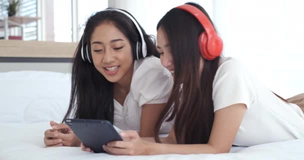 Dos Jóvenes Mujeres Asiáticas Tumbadas Cama Con Auriculares Mientras Hacen — Vídeos de Stock