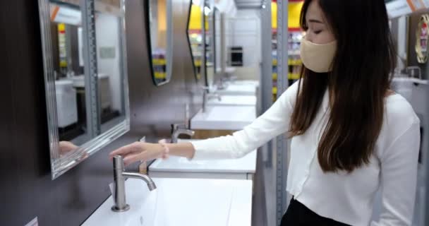 顔のマスクと新しい普通の生活を身に着けている若いアジアの女性 彼女はデパートのバスルームで手を洗う コロナウイルス流行後のショッピングモールセンターは閉鎖され再開しました — ストック動画
