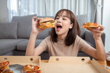 Asyalı kadın hazır yemek ve pizza yerken eve yakın çekim, Fast Food teslimat servisi güvenli ve Coronavirus 'un sosyal uzaklık konseptiyle yayılmasını engeller..
