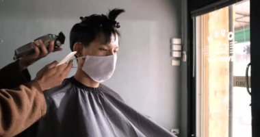 Asya Berber Dükkanı Saç Kesimi Coronavirus tecridinden sonra yüz maskesi takan müşterilerin kuyruğa girmesi, erkeklerin saç modellemesi ve yeni normal yaşam tarzı konsepti.