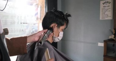 Asya Berber Dükkanı Saç Kesimi Coronavirus tecridinden sonra yüz maskesi takan müşterilerin kuyruğa girmesi, erkeklerin saç modellemesi ve yeni normal yaşam tarzı konsepti.