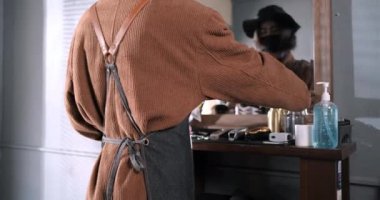 Erkek berber temizlik ekipmanı saç kesiminden önce alkol spreyi ile saç kesme makinesi. Coronavirus kilitleme ameliyatından sonra yüz maskesi takıyor. Yeni erkek saç modelleme normal yaşam tarzı..