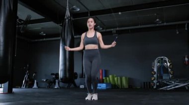 Spor giyimli genç Asyalı kadınlar ip atlama egzersizi spor salonunda ip atlama antrenmanı formda bir kadın spor salonunda ısınıyor Cadio şişman ve sağlıklı yaşam tarzı kavramını yakıyor.. 