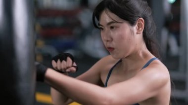 Ağır çekim: Bileklerinde kayış olan genç Asyalı kadın boksör, boks antrenmanına ya da antrenmanına hazırlanan spor elbiseli kadın. Sporcu spor salonuna uyum sağladı. Konsepti geliştirir.