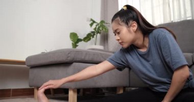 Spor yapan Asyalı genç bir kadın spor yapıyor ve spor videolarını dizüstü bilgisayarında izliyor. Oturma odasında dambıllar, evde spor, çevrimiçi fitness kursu, sağlıklı yaşam tarzı..