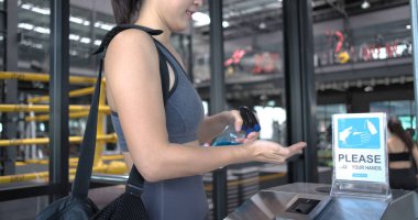 Spor giyim salonu yeniden açılıyor, kadın spor giyim mağazasında lobideyken ellerini dezenfektanla yıkıyor. Coronavirus salgını sırasında spor salonunda çalışmadan önce, sağlıklı bir yaşam tarzı..