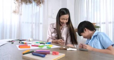 Mutlu Asyalı anne ve küçük oğlu birlikte resim yapıyorlar. Mutlu anne ve kız evde çizim yaparken eğleniyorlar. Yaşam tarzı aile anı.