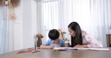 Mutlu Asyalı anne ve küçük oğlu birlikte resim yapıyorlar. Mutlu anne-kız çizim yaparken eğleniyorlar..