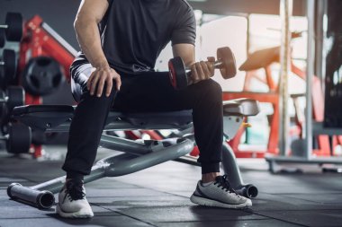 Sporcu dambıllarla egzersiz yapıyor, güçlü erkek spor salonunda formda kalıyor. Hareketli, hareketli, sağlıklı yaşam tarzı, vücut geliştirme, kas kasları odağı.