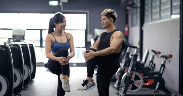 Healthy two people young asian doing stretching leg after workout at fitness gym, Cooldown muscle healthy together, sporty couple teamwork and partner bodybuilding lifestyle concept.