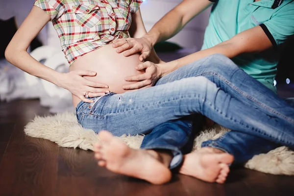 Pareja joven esperando un bebé abrazando el estómago. embarazo y concepto de personas — Foto de Stock