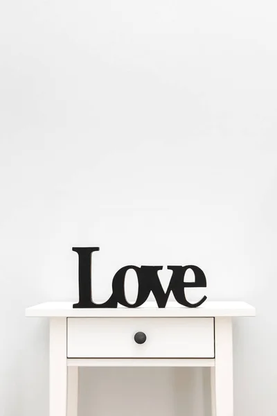 Schwarze Buchstaben Liebe von einem Baum auf einem weißen Tisch. Holzbuchstaben ausschneiden. Buchstaben Liebe auf weißem Hintergrund — Stockfoto