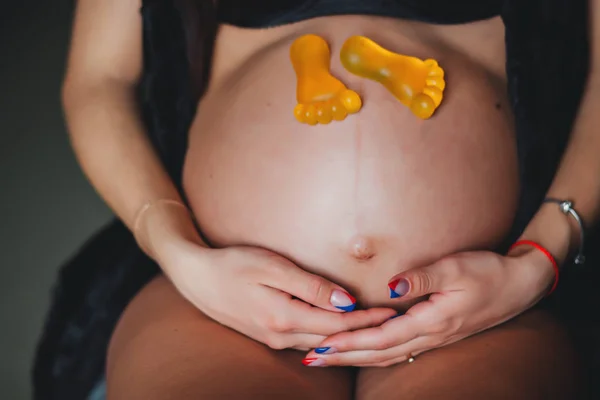 Esperanza del niño. Una mujer embarazada sentada con pies de juguete. Concepto de maternidad . —  Fotos de Stock