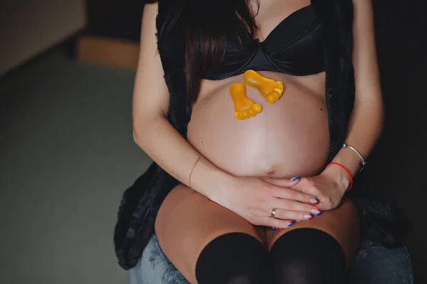 Förväntningar på barnet. En gravid kvinna som sitter med leksak fötter. Moderskap koncept. — Stockfoto