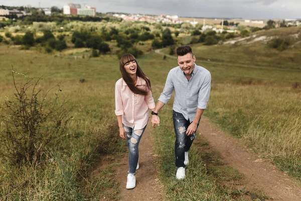 Paar bedrijf handen lopen weg. Portret van een romantische jonge man en vrouw in de liefde in de natuur. het echtpaar klimt omhoog neemt de heuvel — Stockfoto