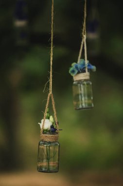 Gül ve ormanda ağaçların arasında bir iş parçacığı üzerinde askıya diğer çiçek düğün süslemeleri küçük şişeler gelen dolu