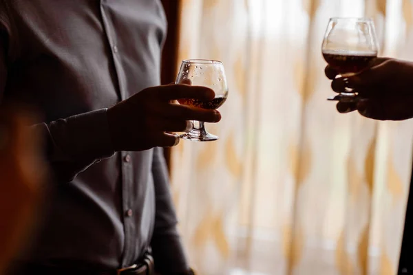 Männer mit einem Freund, der am Fenster steht. halten Sie in den Händen von Gläsern Whiskey. Nahaufnahme — Stockfoto