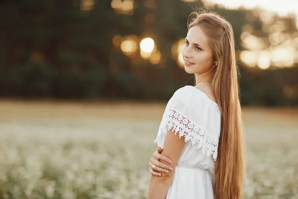 Retrato de una hermosa niña en un vestido blanco en un campo floreciente. Campo de flores. Verano. unidad con la naturaleza . — Foto de Stock