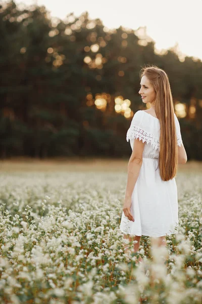 Retrato de una hermosa niña en un vestido blanco en un campo floreciente. Campo de flores. Verano. unidad con la naturaleza . — Foto de Stock