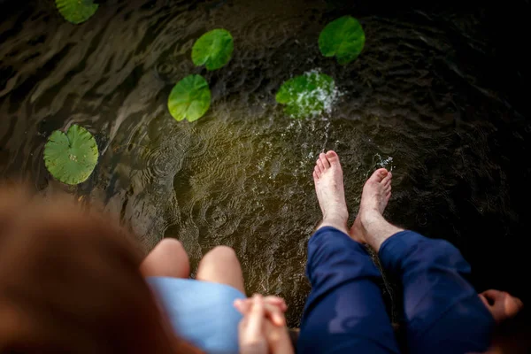 在日落时, 情侣们的脚在水中溅起水花 — 图库照片