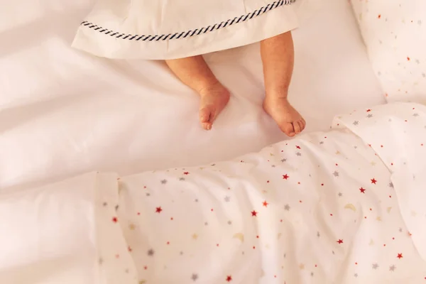Ноги дитини на ліжку. маленькі дитячі ноги в сукні. вид зверху — стокове фото