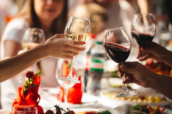 Cheers. People celebrate and raise glasses of wine for toast. Group of man and woman cheering with sparkling champagne in rooftop restaurant