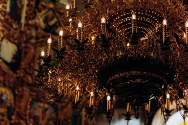 Altın kaplama avize simgeleri yanında eski kilise asılı. Mumlar gibi modern lambalar vardır.