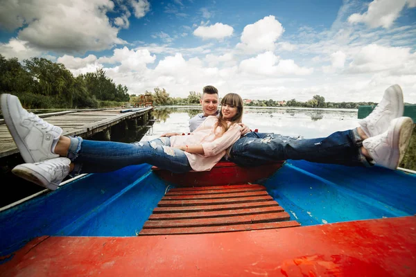 Um casal montando um barco azul em um lago. Romance. casal emocional. engraçado e apaixonado — Fotografia de Stock