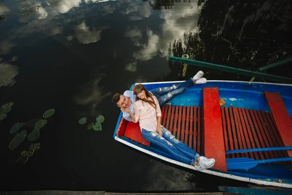 A couple riding a blue boat on a lake. romance. emotional couple. funny and in love