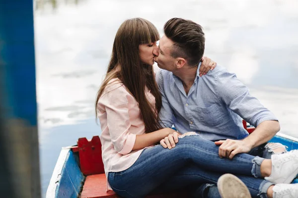 Um casal montando um barco azul em um lago. Romance. casal emocional. engraçado e apaixonado — Fotografia de Stock