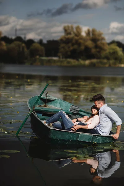 Estou só a relaxar. Belo jovem casal desfrutando de encontro romântico enquanto remo um barco. Casal amoroso descansando em um lago enquanto monta um barco verde. romance . — Fotografia de Stock