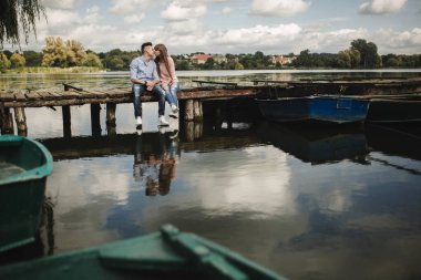 İdeal an... Güzel genç çift kucaklayan ve iskelede otururken gülümseyen