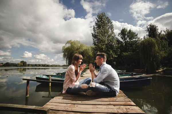 Idealer Moment.. schönes junges Paar umarmt und lächelt, während es auf der Seebrücke sitzt — Stockfoto