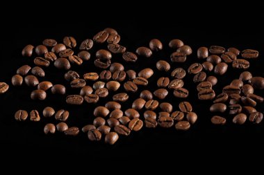 koyu kavrulmuş kahve çekirdekleri düzenlenmiştir. Kahve çekirdekleri yakın çekim. kahve siyah bir zemin üzerine