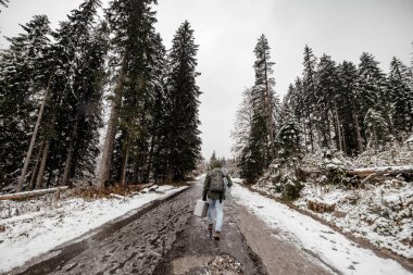 gidiş karlı bir orman yoluyla bir sırt çantası ile turist adam. geniş açı