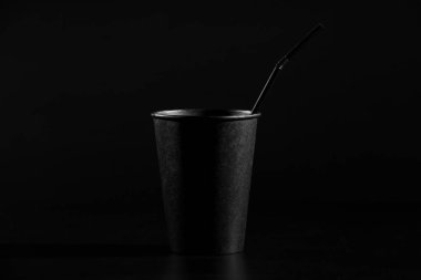 siyah kağıt cam bir tüp siyah bir arka plan ile. bir bardak kahve veya çay plastik bir kapak ile