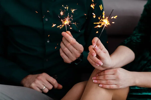 Um casal com luz de bengala. Mãos masculinas e femininas seguram luzes iluminadas de Bengala. Bela família jovem feliz celebrando o Natal juntos . — Fotografia de Stock