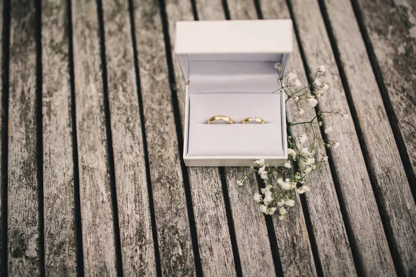 Alianças de casamento em uma caixa na mesa. pequenas flores em uma mesa de madeira — Fotografia de Stock