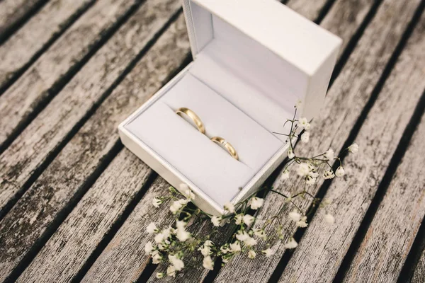 Alianças de casamento em uma caixa na mesa. pequenas flores em uma mesa de madeira — Fotografia de Stock