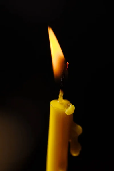 Brennende Kerze auf schwarzem Hintergrund. Kerzenschein. die Flamme des Kerzenlichts. — Stockfoto
