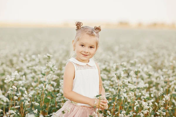 Retrato infantil de uma menina. menina bonita em um campo de floração. Jovem jogar no campo de dente-de-leão primavera — Fotografia de Stock