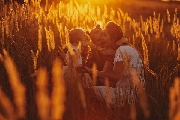 Familia feliz, mamá y dos hijas. Mamá juega con su hija en la calle al atardecer. concepto familiar — Foto de Stock