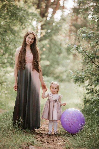 Mère et fille avec des ballons. Belle mère heureuse avec sa fille qui s'amuse dans un champ vert tenant des ballons. Maman, gosse, mère . — Photo