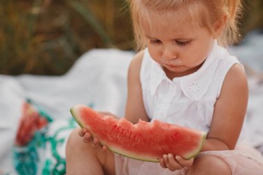 Bahçede karpuz yeme çocuk. Çocuklar açık havada meyve yiyin. Çocuklar için sağlıklı snack. Bir dilim karpuz tutan bahçede oynayan küçük bir kız. Çocuk Bahçe