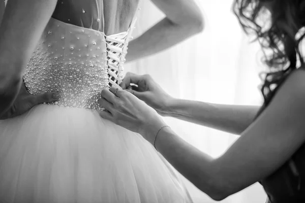 Damigella d'onore aiutare sposa fissare corsetto e ottenere il suo vestito, preparando sposa al mattino per il giorno del matrimonio. riunione della sposa . — Foto Stock
