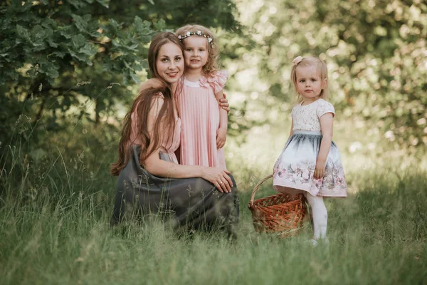 Un magnifique portrait de maman avec deux filles dans le parc. Mère et deux filles tourbillonnant. Mère tient ses filles sur ses mains. Du temps en famille ensemble . — Photo