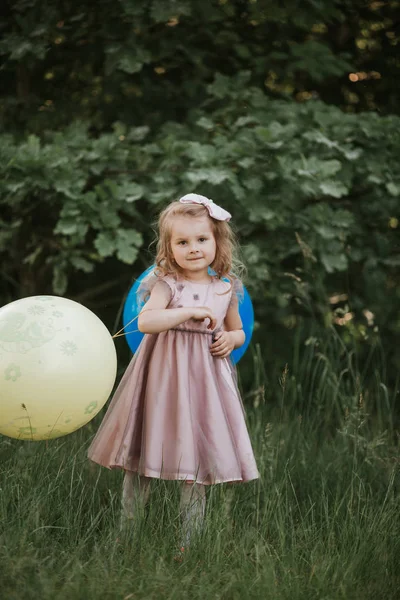 Stylová holčička 4-5 rok stará s velkým balonem s módním růžovým oblečením na louce. Hravý. Holčička s balonem v parku. Oslava narozenin. — Stock fotografie