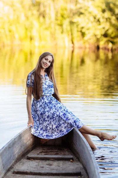 Retrato de estilo de vida de una mujer joven y hermosa sentada en una lancha. chica divirtiéndose en barco en el agua. La chica se sienta en un barco en un lago — Foto de Stock