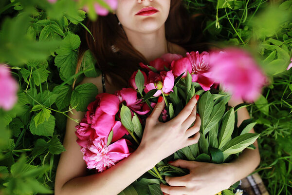 Bouquet of Peony. Stylish fashion photo of beautiful young woman lies among peonies. Holidays and Events. Valentines Day. Spring blossom. Summer season