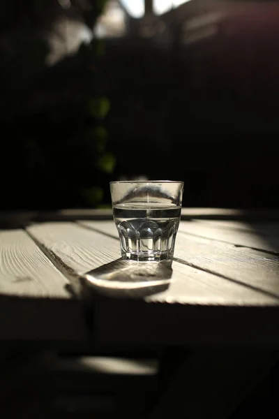 Helder water in een helder glas tegen. Gezond voedsel en milieuvriendelijk natuurlijk water. een glas water op een houten tafel. — Stockfoto